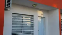 Entrada de un departamento Pewmafe en Las Grutas, con galería techada, aire acondicionado y ventana con reja blanca
