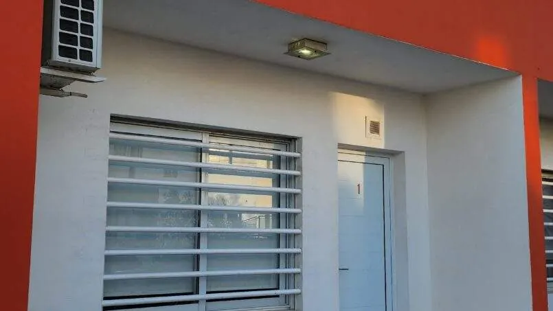 Entrada de un departamento Pewmafe en Las Grutas, con galería techada, aire acondicionado y ventana con reja blanca