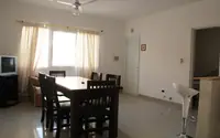 Living comedor del departamento de 2 ambientes del Complejo Luminar en Las Grutas, con mesa para seis, TV y ventilador de techo