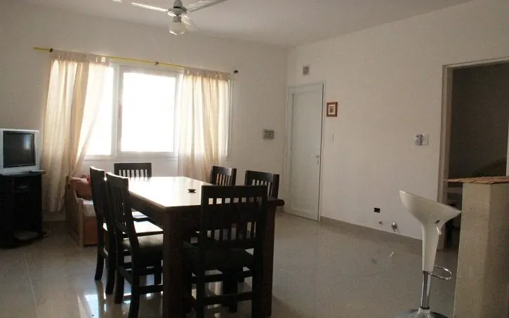 Living comedor del departamento de 2 ambientes del Complejo Luminar en Las Grutas, con mesa para seis, TV y ventilador de techo