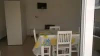 Comedor del monoambiente Luminar en Las Grutas con TV, mesa para cuatro y salida al solárium