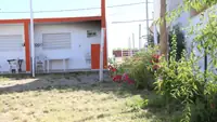 Jardín del complejo Pewmafe en Las Grutas con galerías, mesas al aire libre y plantas con flores