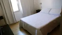 Dormitorio del Departamento LG en Las Grutas con cama doble, cortinas y mesa de luz
