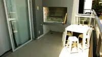 Parrilla del balcón del Departamento LG en Las Grutas, con mesa alta y banquetas