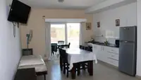 Living comedor del Departamento LG en Las Grutas con ventanal corredizo al balcón con parrilla