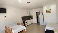 Living comedor del departamento Pewmafe en Las Grutas con mesa para cuatro, Smart TV, cocina integrada y heladera