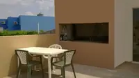 Solárium con parrilla del departamento de 2 ambientes del Complejo Luminar en Las Grutas, con mesa y sillas