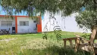 Parque con césped y árboles del complejo Pewmafe en Las Grutas, con reposeras a la sombra